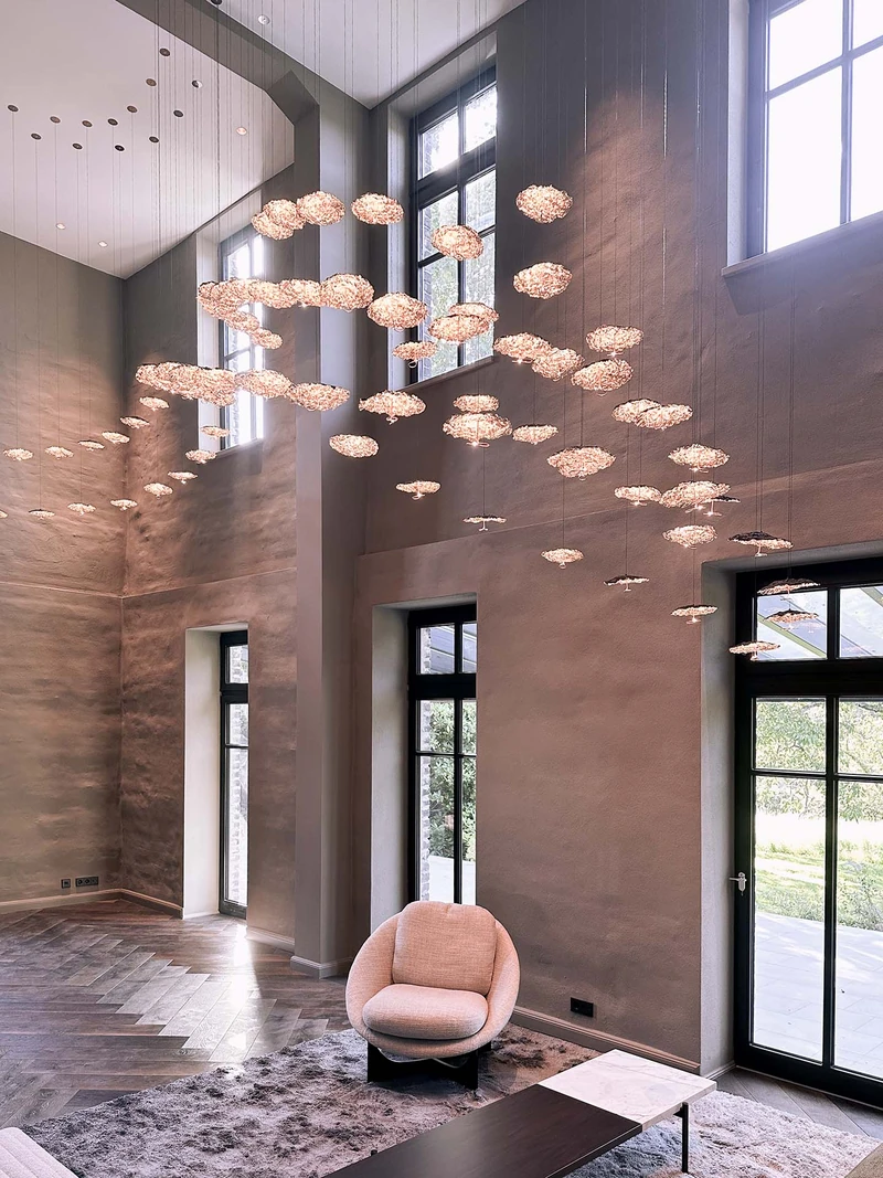 Hohe Wand in warmem Grau mit Sprossenfenstern, Lichtinstallation und Sessel