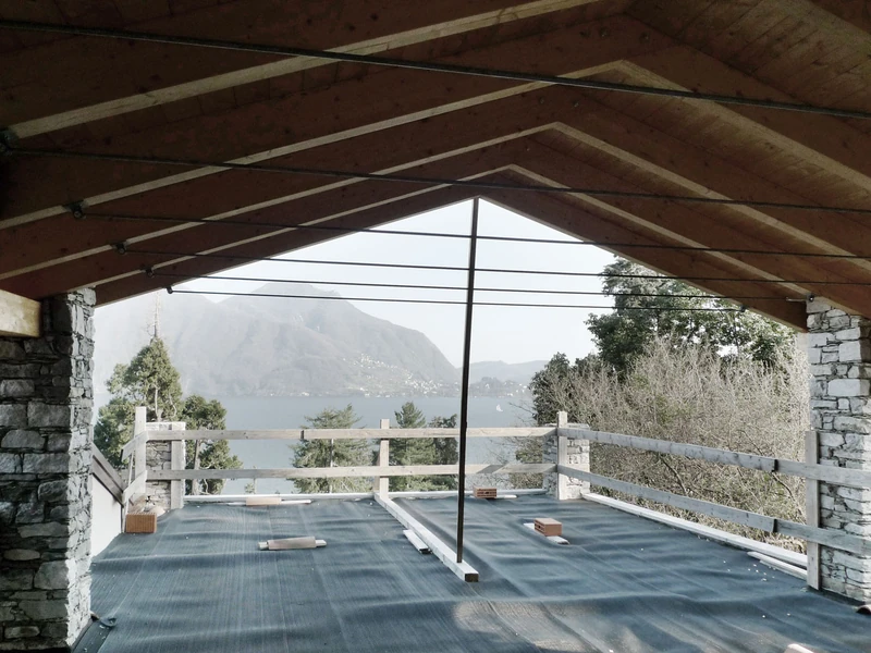 Überdachte Dachterrasse im Bau mit Blick auf See und Berge