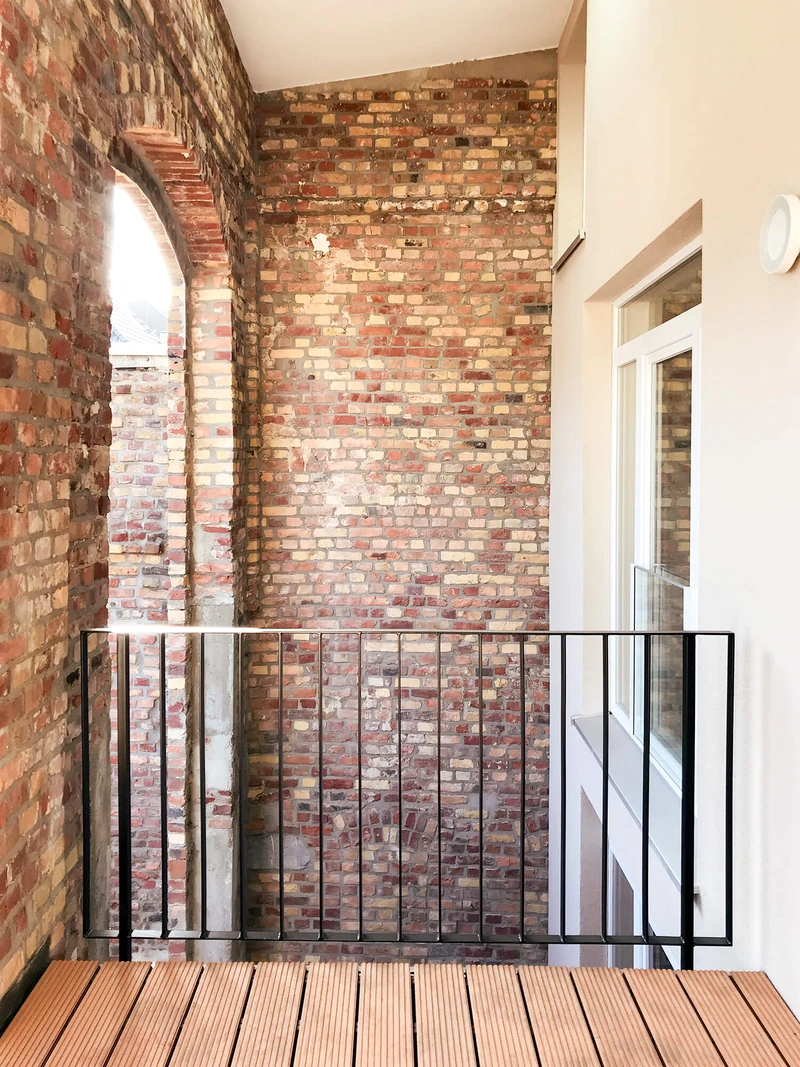 Loggia mit Backsteinwänden, Holzboden und Stahlgeländer