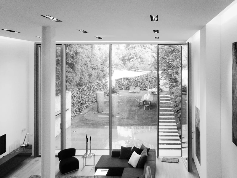 Wohnbereich mit Loft-Charakter und raumhoher Verglasung zum Garten, schwarzweiß