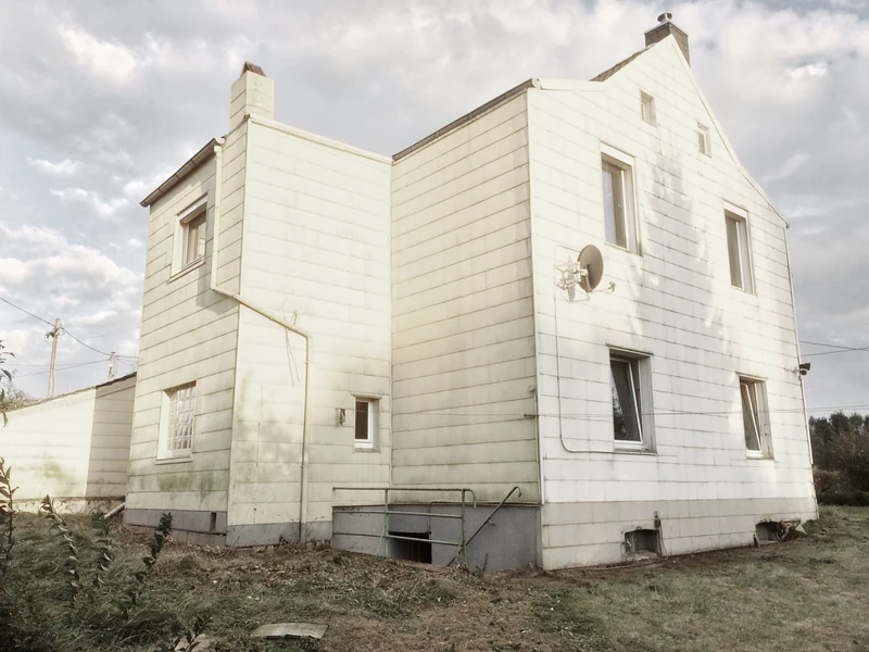 Bestand: Einfamilienhaus mit heller Plattenfassade vor der Revitalisierung