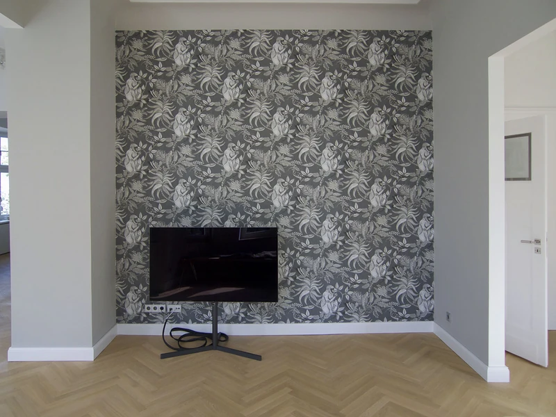 Wohnraum mit gemusterter Tapetenwand und Fernseher auf Standfuß