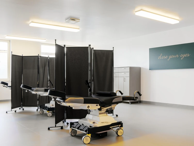 Behandlungsbereich mit Patientenliegen und schwarzen Stellwänden