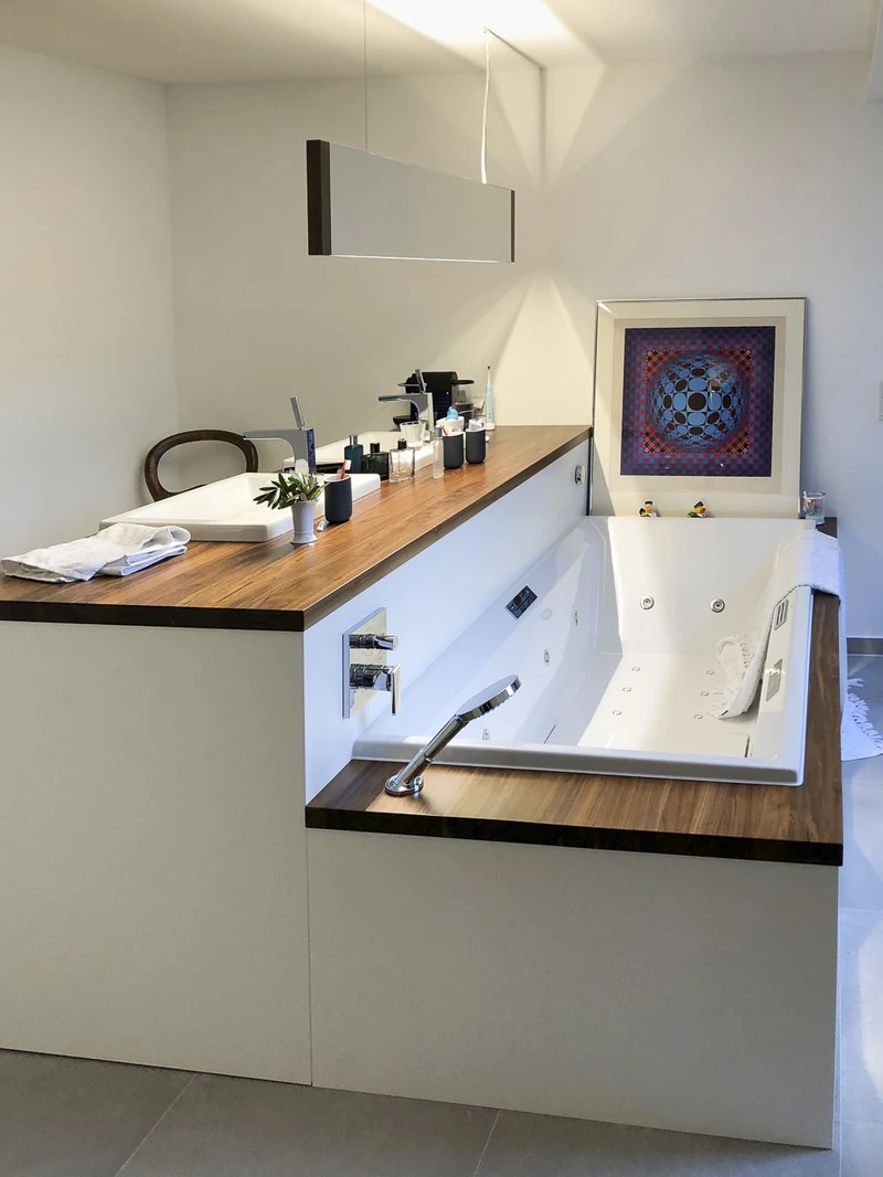 Badewanne mit Einfassung aus Nussbaum und Kunstwerk an der Wand