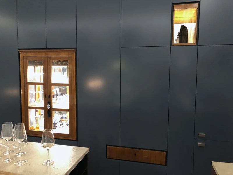 Blaugraue Schrankwand mit eingelassener historischer Vitrine
