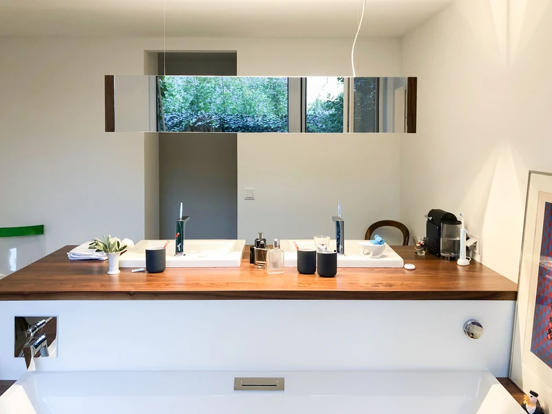 Waschtisch mit Spiegelband und Badewanne im Vordergrund