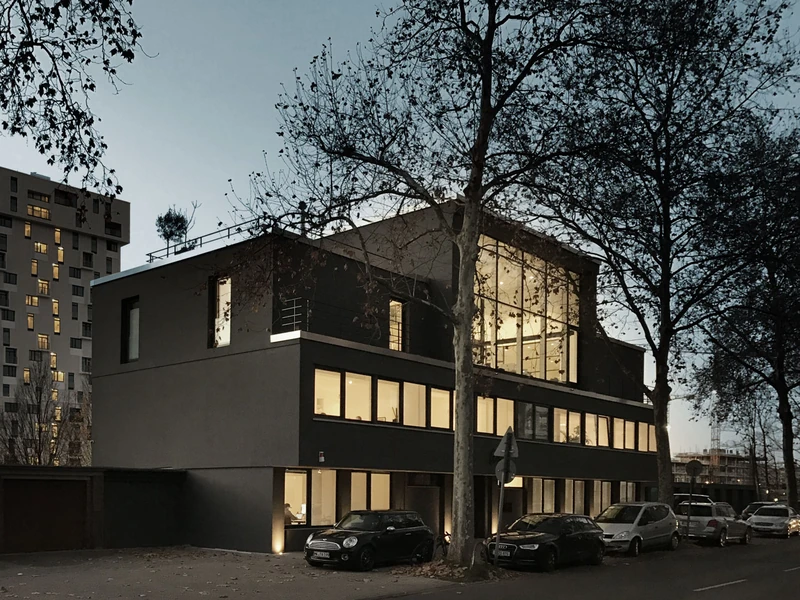 Umgebautes und aufgestocktes Gebäude mit dunkler Fassade in der Abenddämmerung