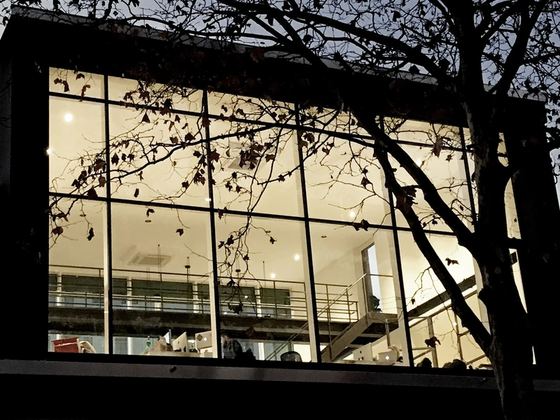 Beleuchtete Glasfassade bei Nacht mit Blick auf Galerie und Treppe