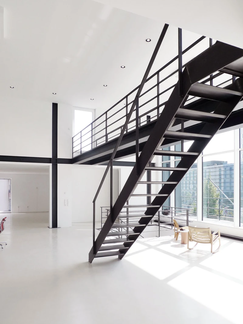 Schwarze Stahltreppe zur Galerie vor großer Glasfassade