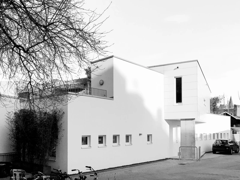 Neubau mit weißer Fassade und auskragendem Obergeschoss, schwarzweiß