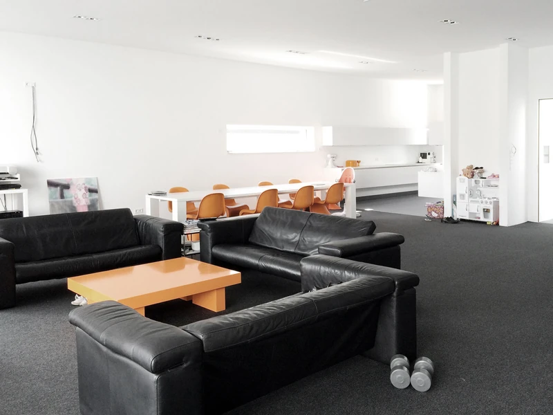 Offener Wohnbereich mit Ledersofas und langem Esstisch